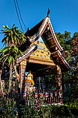 Wat Xieng Thong temple in Luang Prabang, Laos. The small pavilion with a seated Buddha statue. 